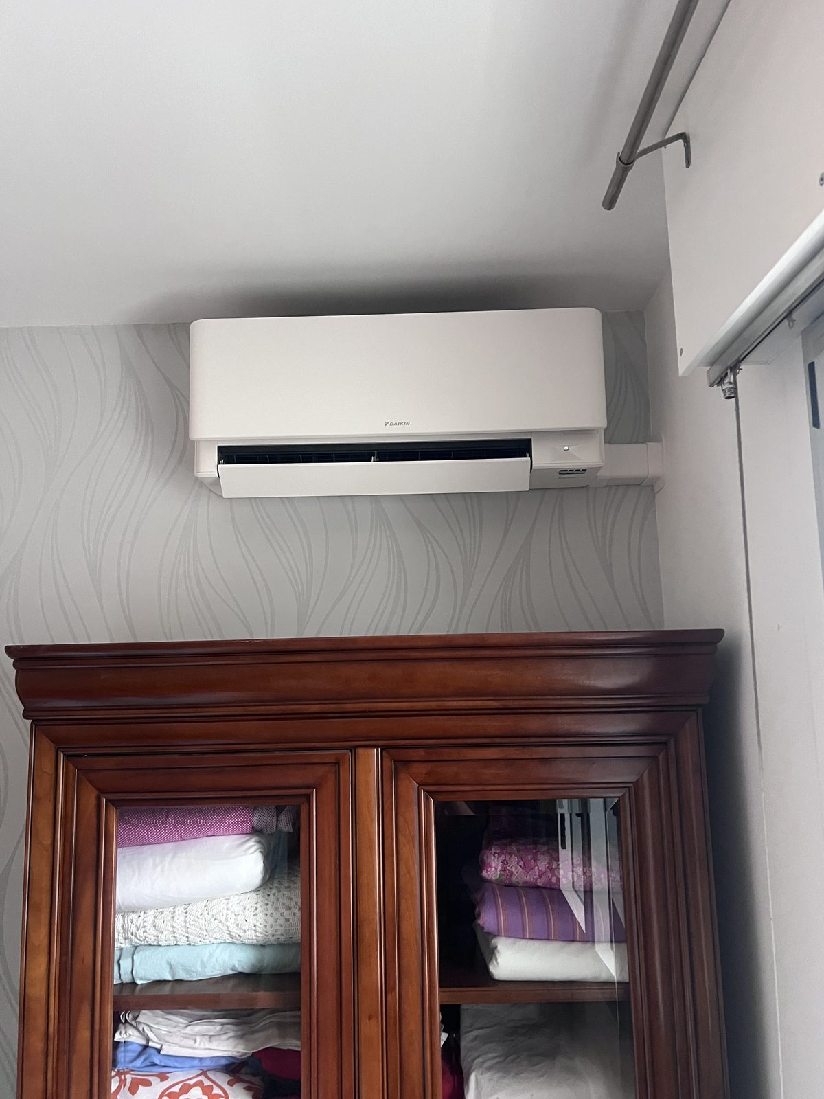 Unité murale Daikin installée au-dessus d'une armoire dans une chambre